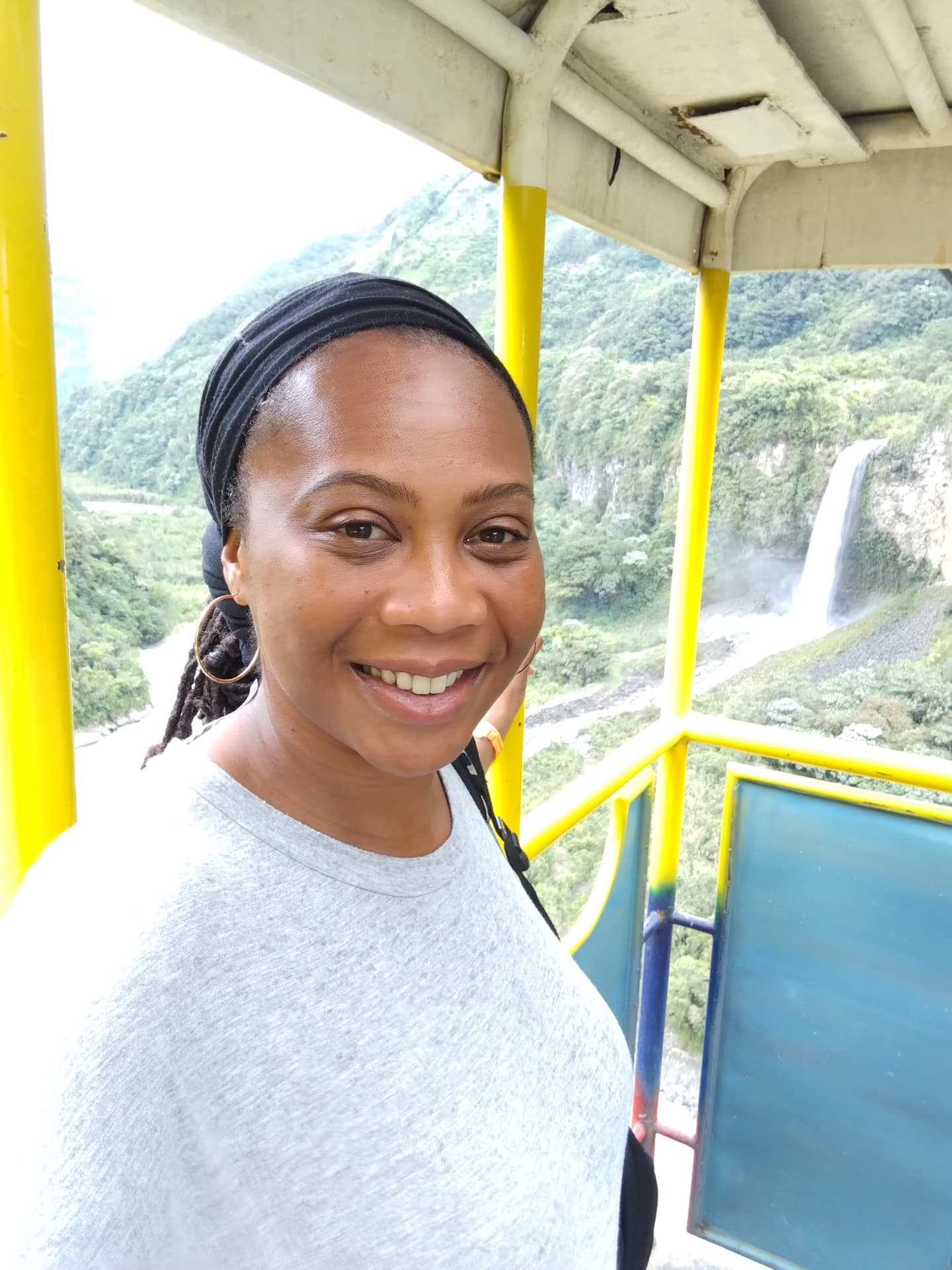 Adorned Itiya smiling with a waterfall and mountain landscape behind her